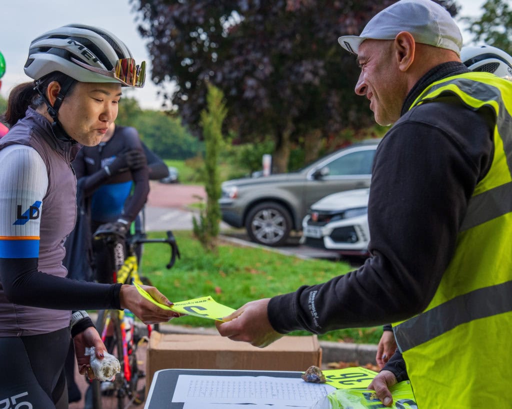 Hill climb volunteer handing out a riders race number