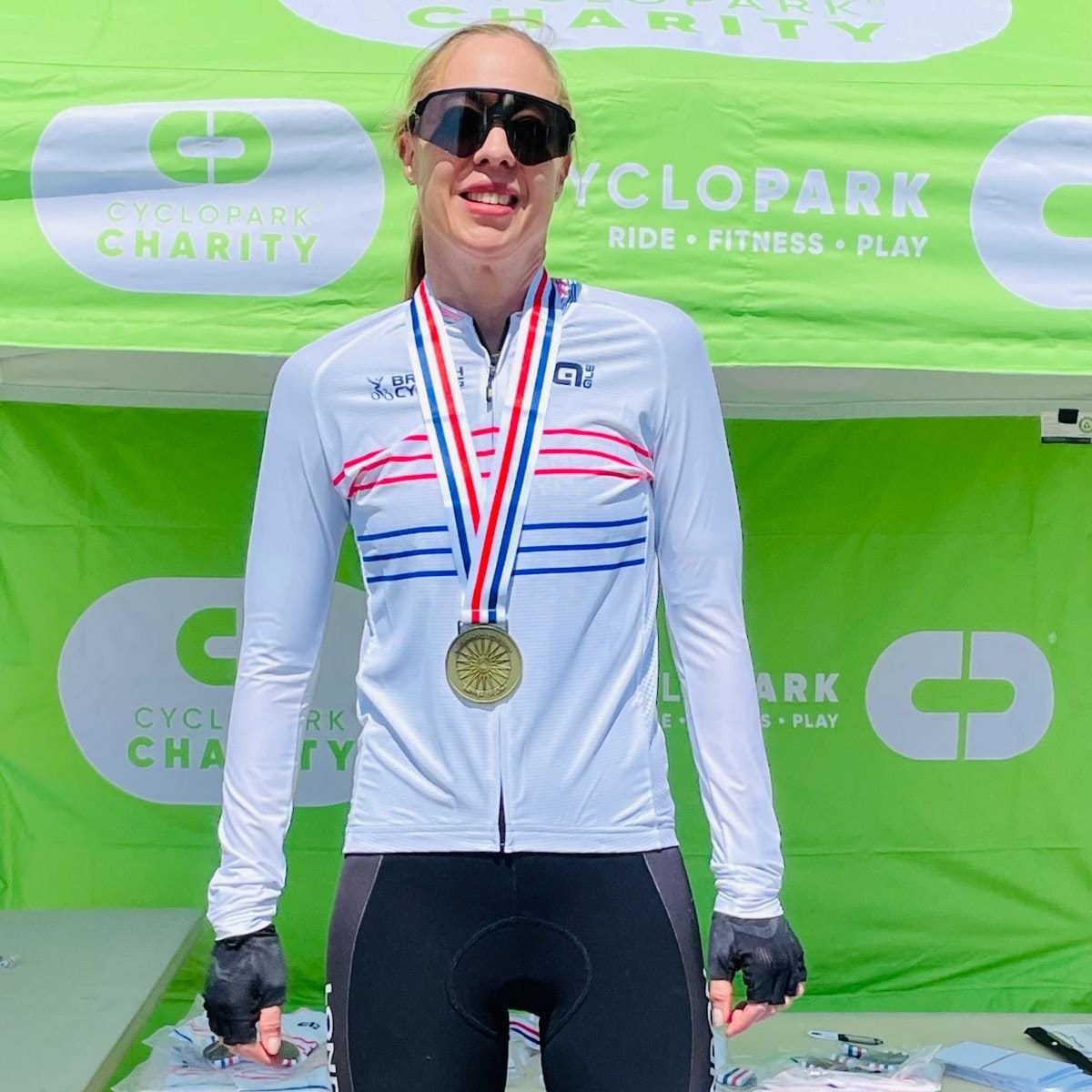 Alexandra Hamilton wearing her national champion's medal in front of a Cyclopark banner