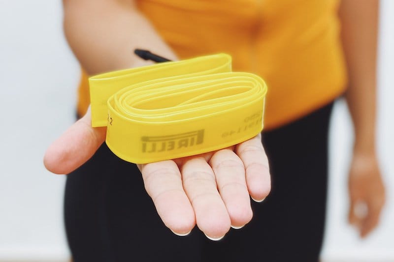 A hand holding a folded yellow TPU inner tube