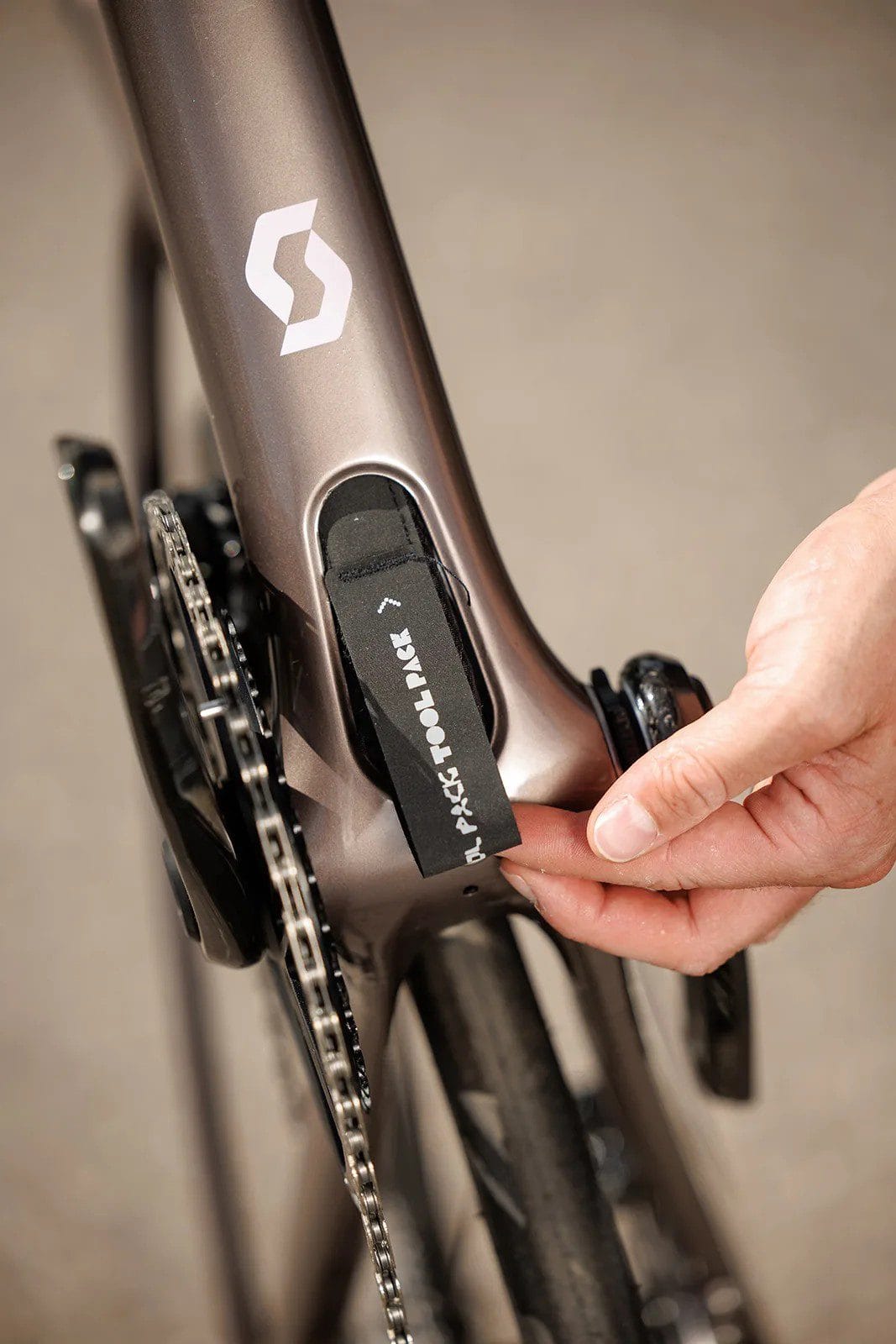 Hand pulling a tool compartment from the down tube of a Scott Addict road bike